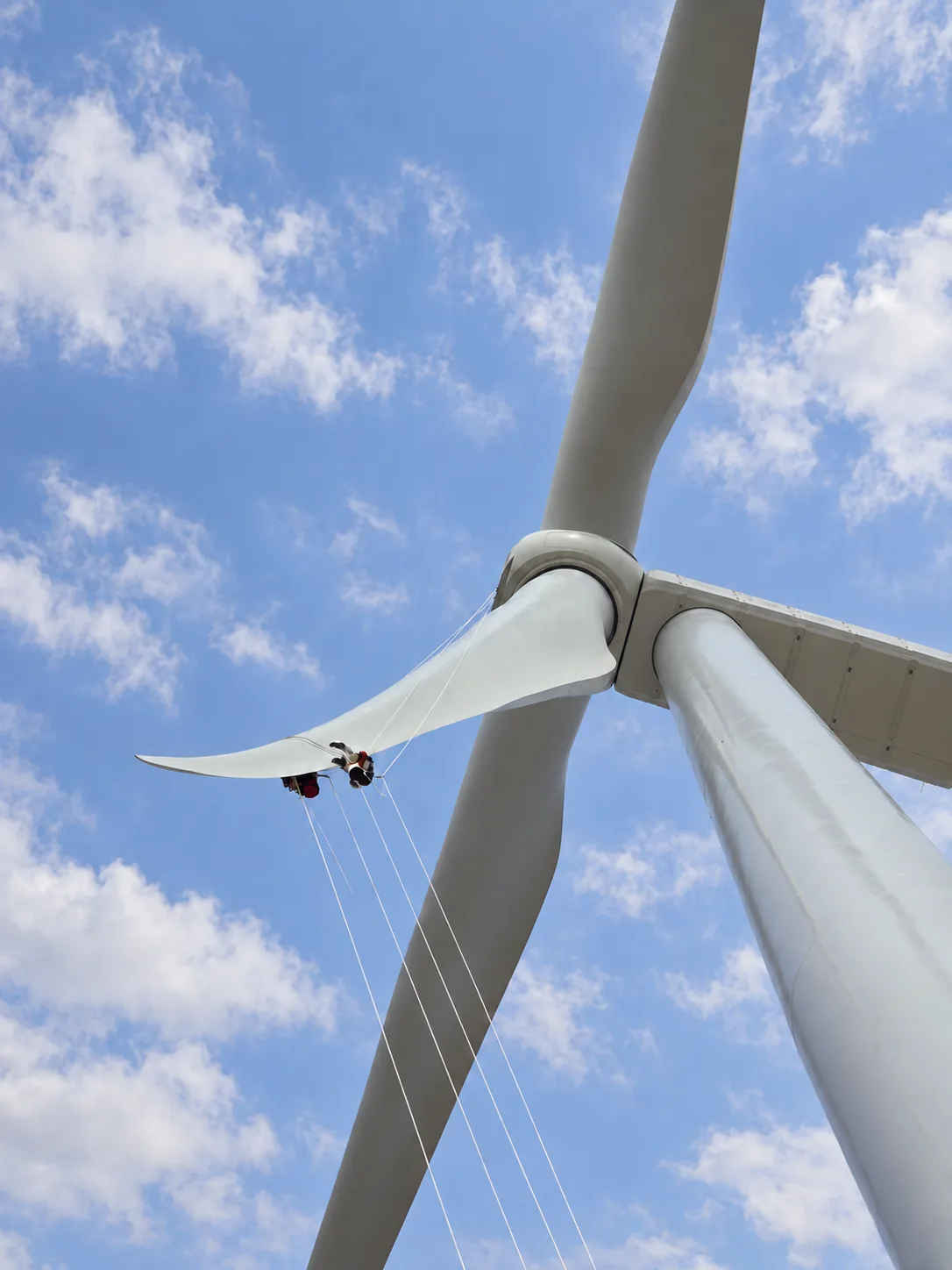 Técnicos de acceso por cuerdas suspendidos bajo una pala de aerogenerador