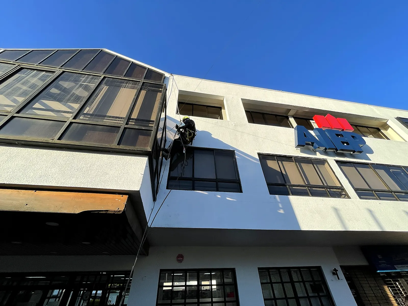 Técnico de VERTEC trabajando en las ventanas de la fachada de un edificio institucional con acceso por cuerdas