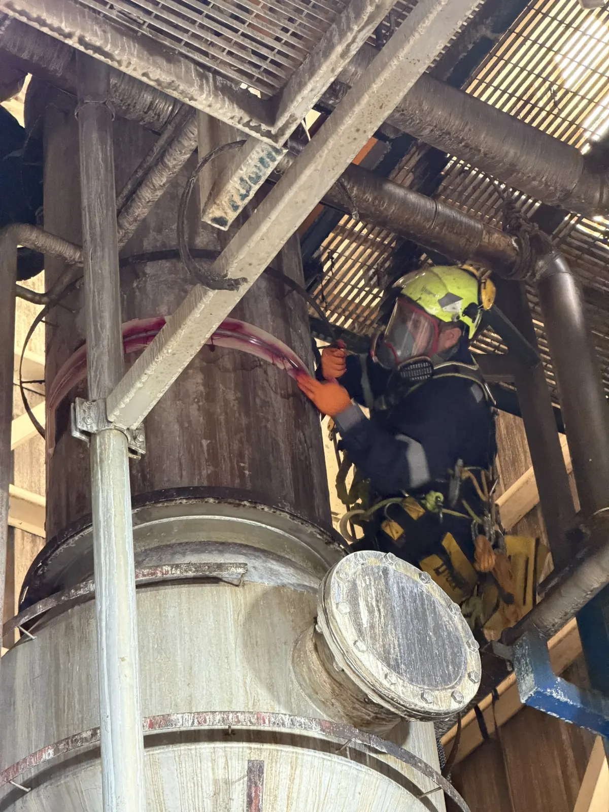 Técnico de VERTEC en acceso por cuerdas aplicando tinte penetrante rojo sobre una soldadura en altura