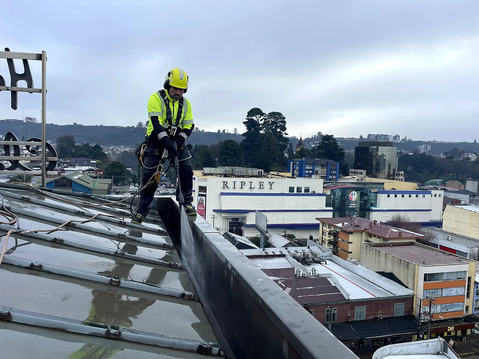 Técnico de VERTEC limpiando con hidrolavado la canaleta de la cubierta de un edificio