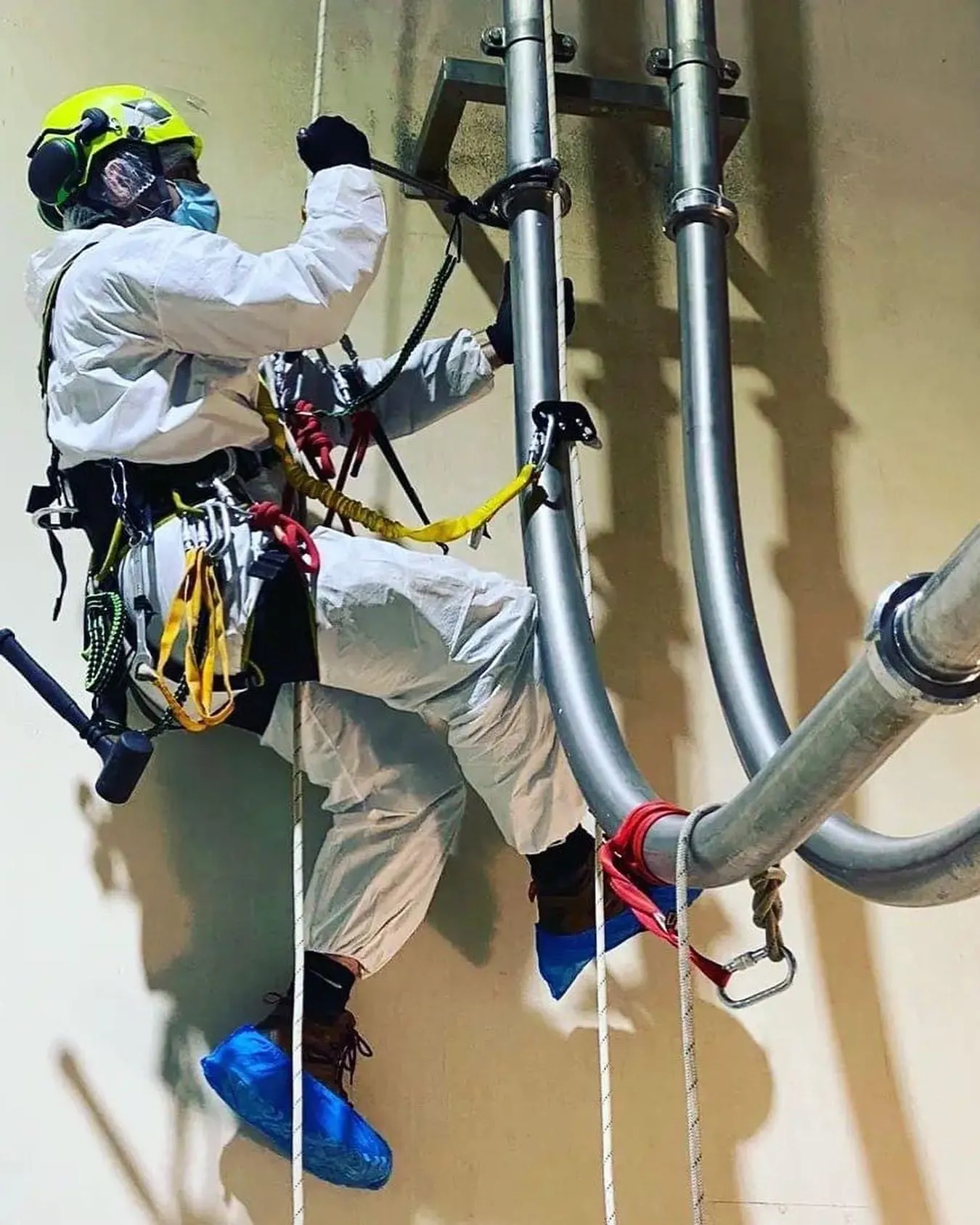 Técnico de VERTEC en acceso por cuerdas montando tuberías de acero inoxidable en altura