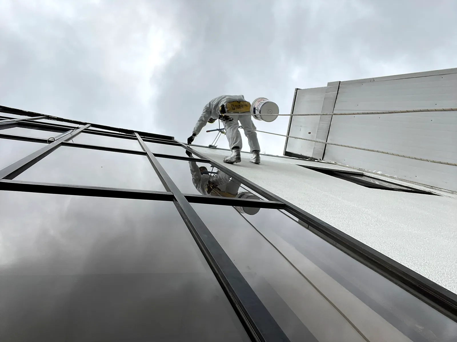 Técnico de VERTEC pintando el muro de un edificio en altura con acceso por cuerdas