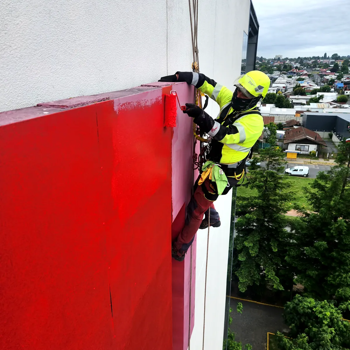 Técnico de VERTEC pintando con rodillo un elemento de fachada en altura con acceso por cuerdas
