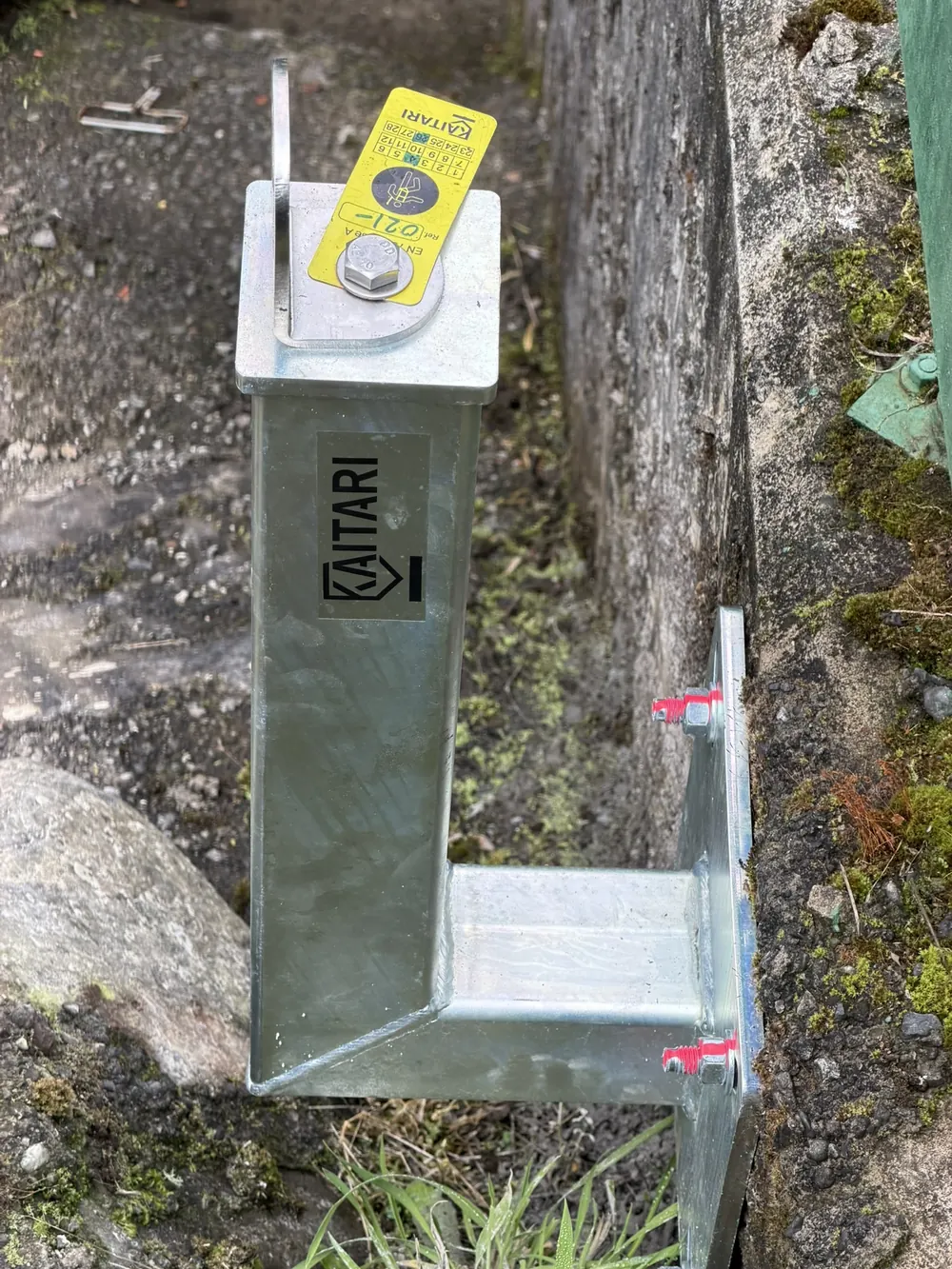 Poste galvanizado con punto de anclaje fijado lateralmente a un muro