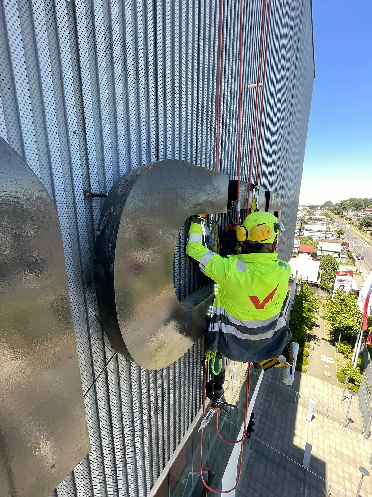 Técnico de VERTEC reparando la iluminación LED de una letra corpórea en la fachada de un edificio con acceso por cuerdas