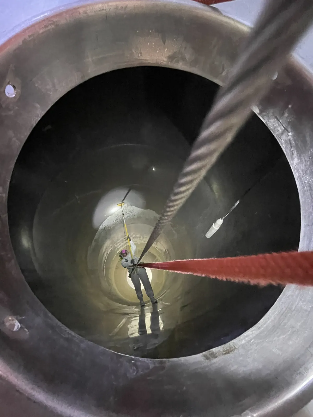 Técnico de VERTEC trabajando dentro de un estanque visto desde la entrada superior