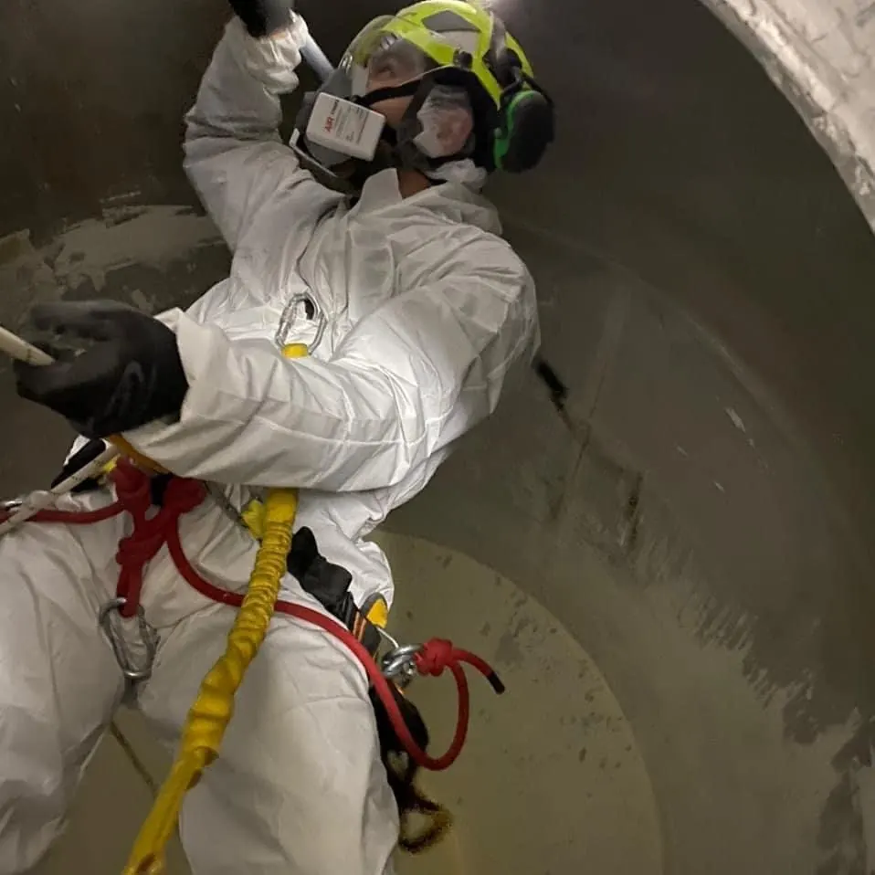 Técnico de VERTEC con protección respiratoria limpiando el interior de un estanque