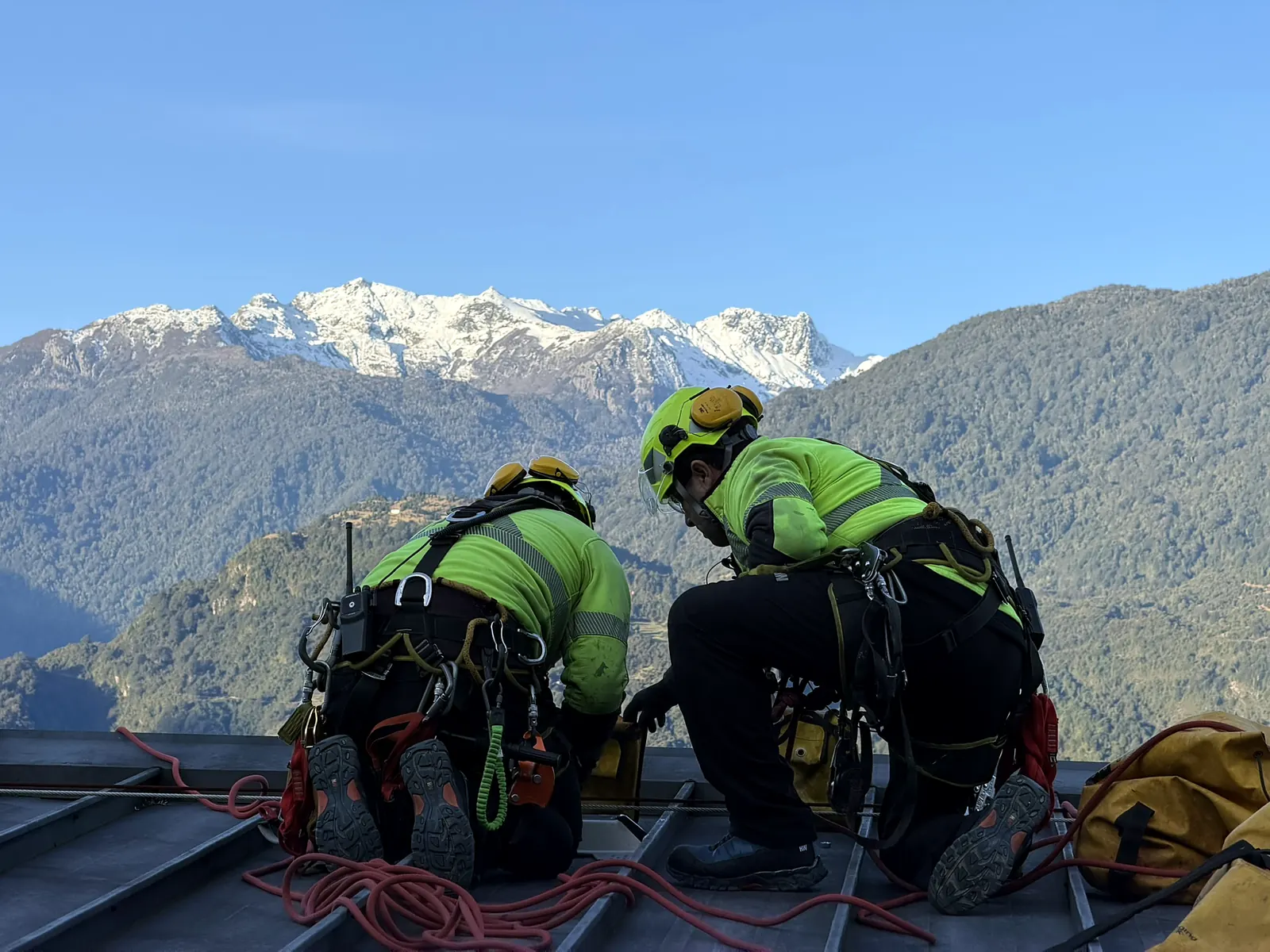 Técnicos de VERTEC preparando un trabajo en una cubierta con la cordillera de fondo