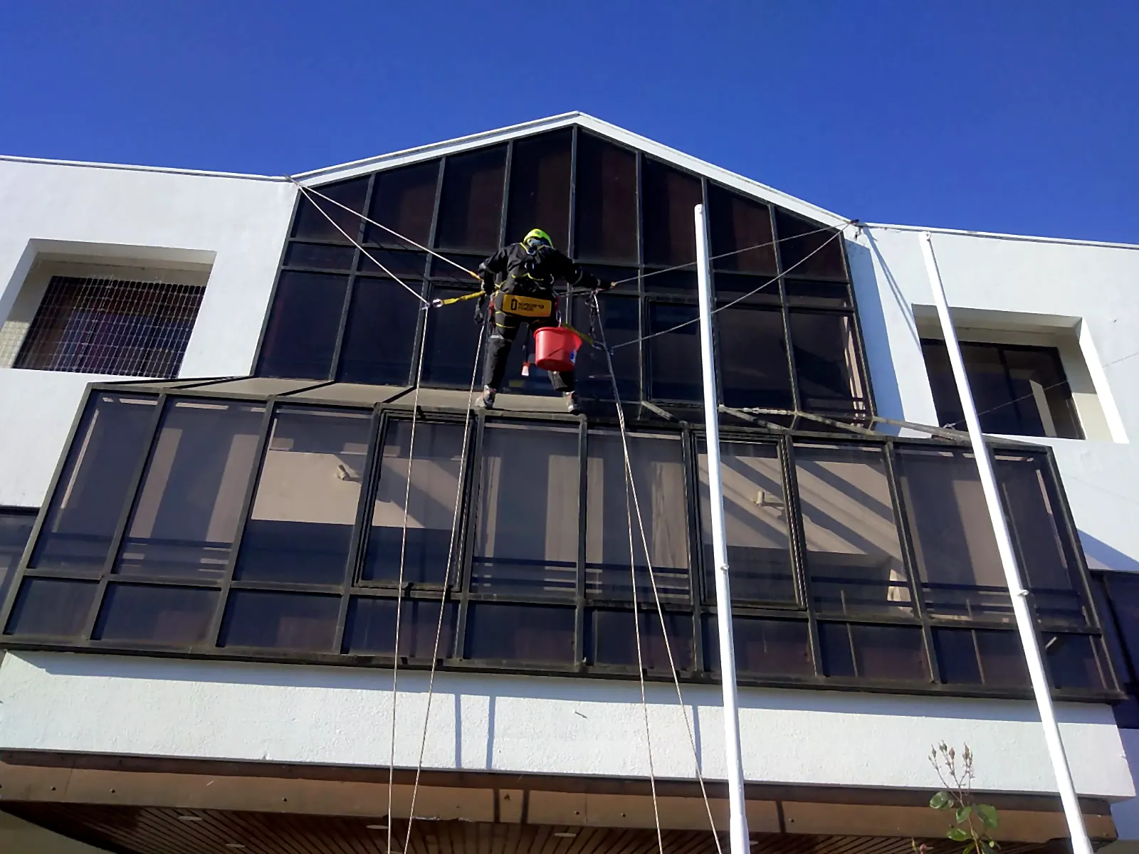 Técnico de VERTEC trabajando sobre el muro cortina de vidrio de un edificio con acceso por cuerdas