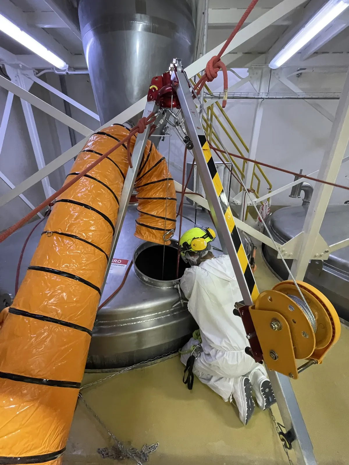 Técnico de VERTEC preparando el ingreso a un estanque con trípode, malacate y ventilación forzada