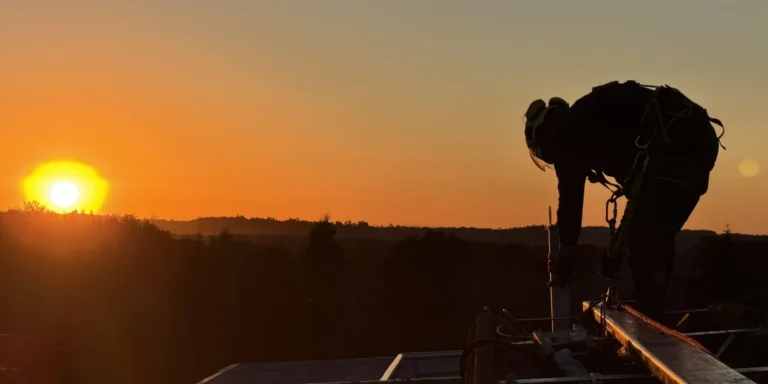 Técnico de VERTEC instalando una línea de vida permanente sobre una cubierta al atardecer